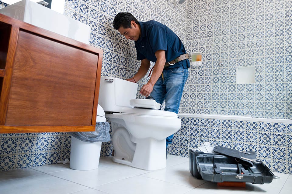 Plumber fixing a toilet in the bathroom
